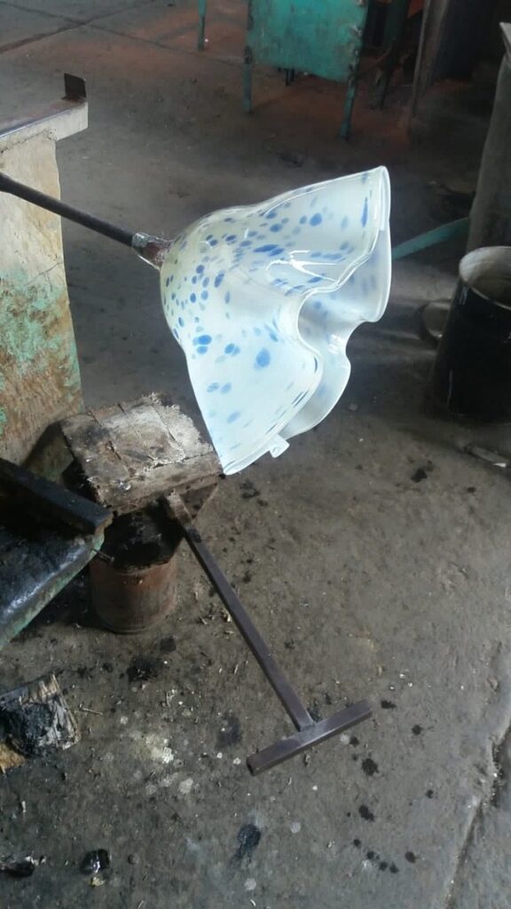 Flor de vidrio soplado blanco con puntos azules recién salida del horno en el taller de Kublaikan en Tonalá